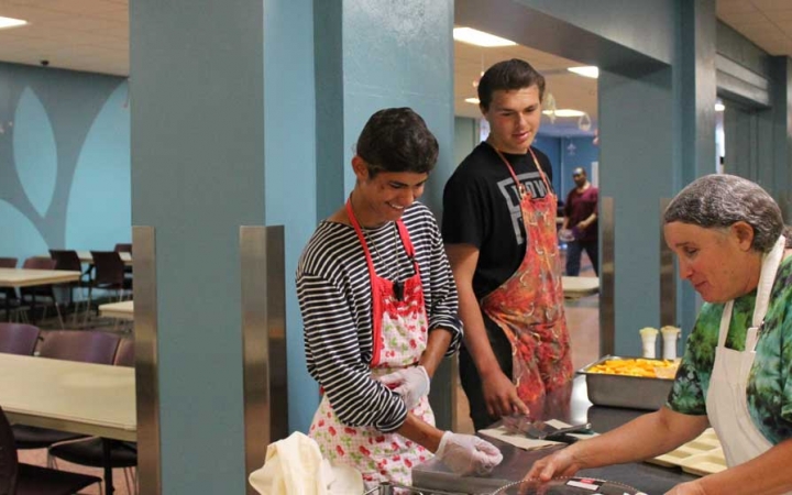 Young people prepare food during a service project with outward bound.